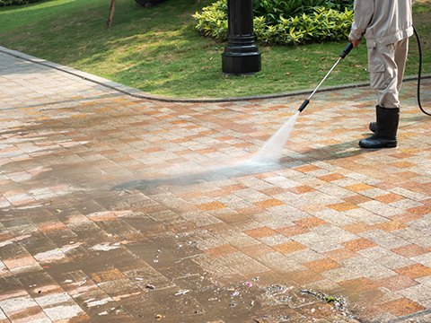 a person using a pressure washer to clean a driveway