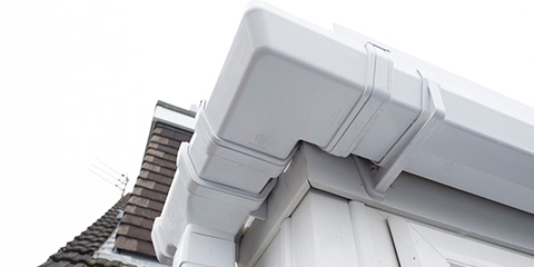 a white PVC gutter clean and on the corner of a house