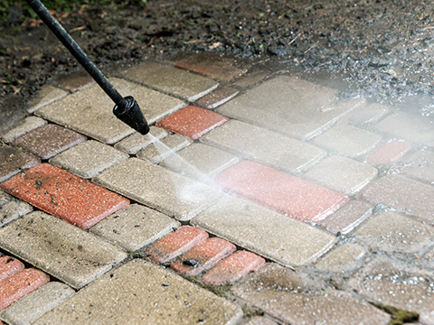 a person using a pressure washer to clean a very muddy patio