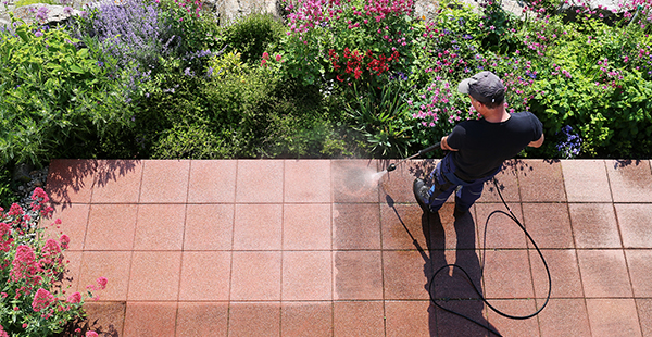 a person using a washer to wash stones on a patio in a garden